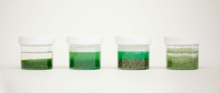 four coated sand products in jars full of water